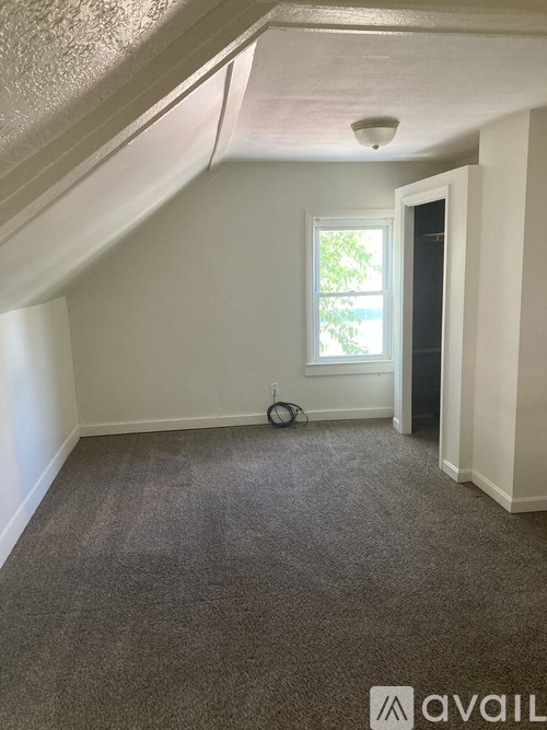 A room with a window and a smoke detector on the ceiling.