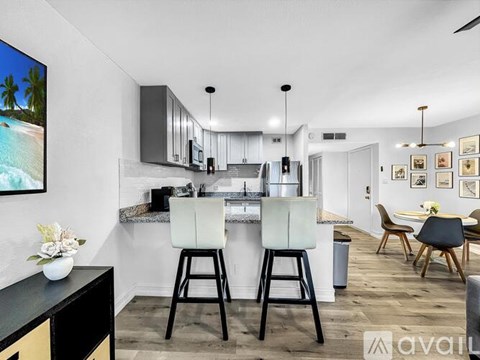A modern kitchen with white cabinets and black stools.