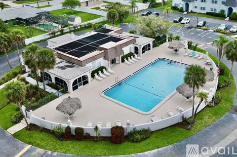 A large swimming pool surrounded by a white fence and a building with a solar panel on the roof.
