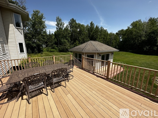 A wooden deck with a table and chairs and a gazebo.