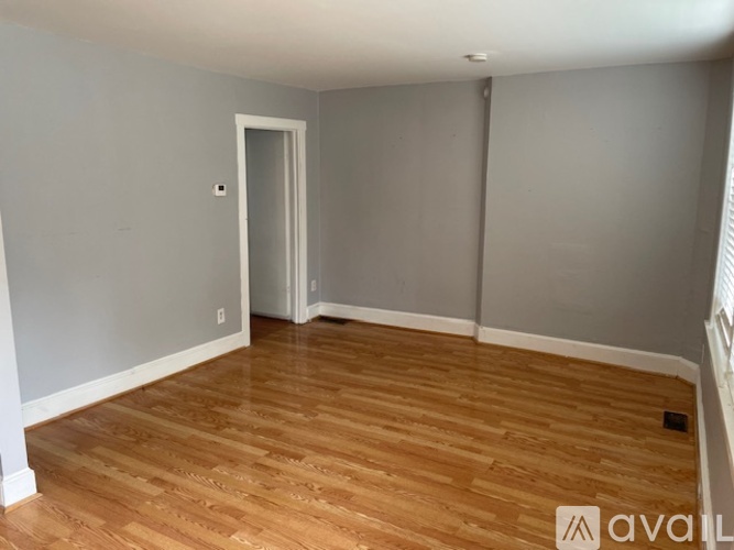 A room with wooden flooring and a doorway leading to another room.
