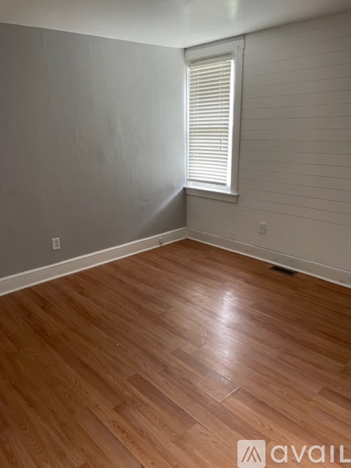 A room with wooden flooring and a window with blinds.