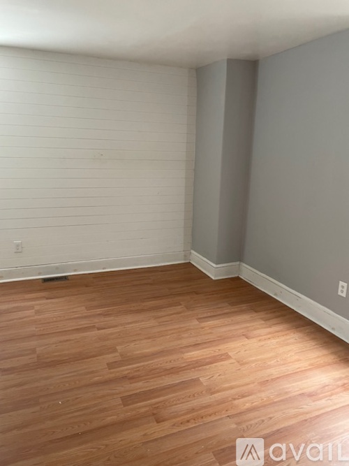 A room with wooden flooring and white walls.