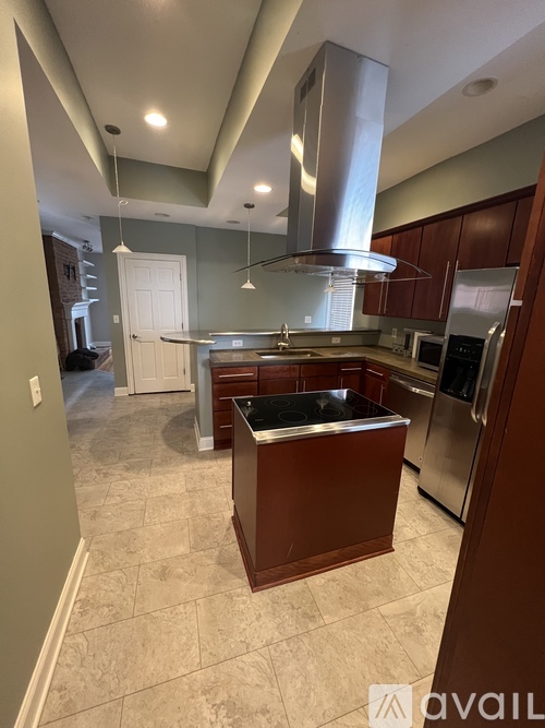 A kitchen with a stainless steel range hood and a dark wood island.