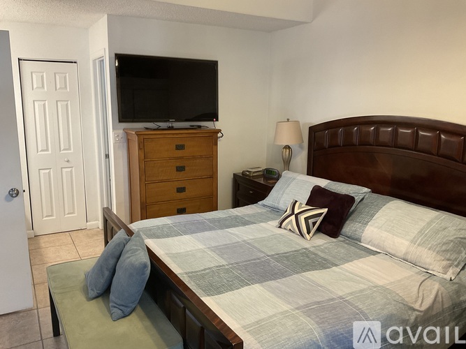 A bedroom with a bed, nightstand, and television.