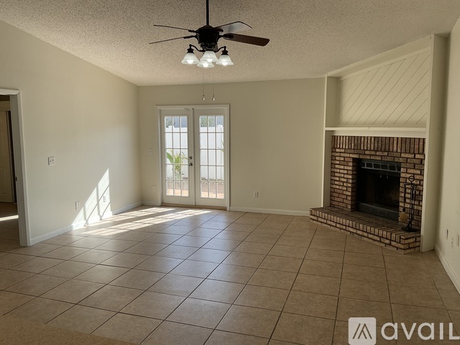 A living room with a fireplace and a ceiling fan.