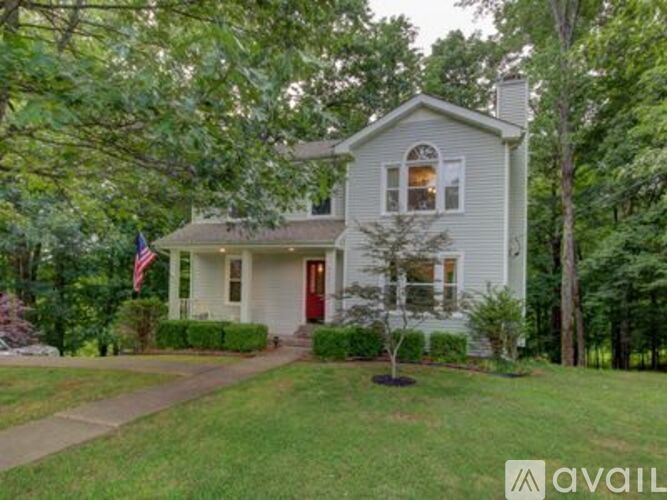 A house with a red door is surrounded by greenery.