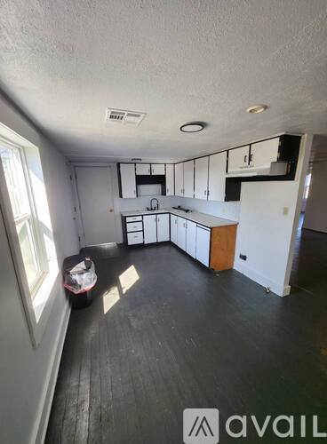 A kitchen with white cabinets and a black floor.