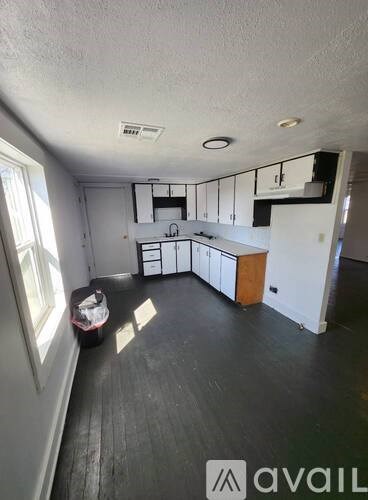 A kitchen with white cabinets and a black floor.