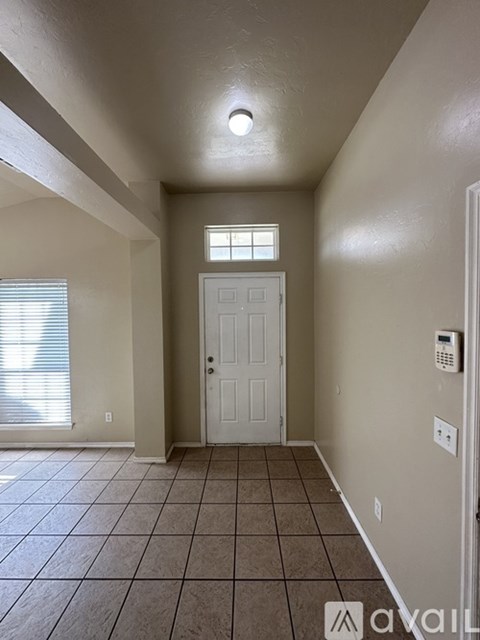 A tiled hallway with a white door and a window.