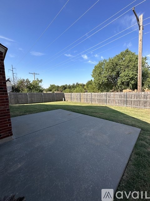 A concrete patio with a fence and trees in the background.