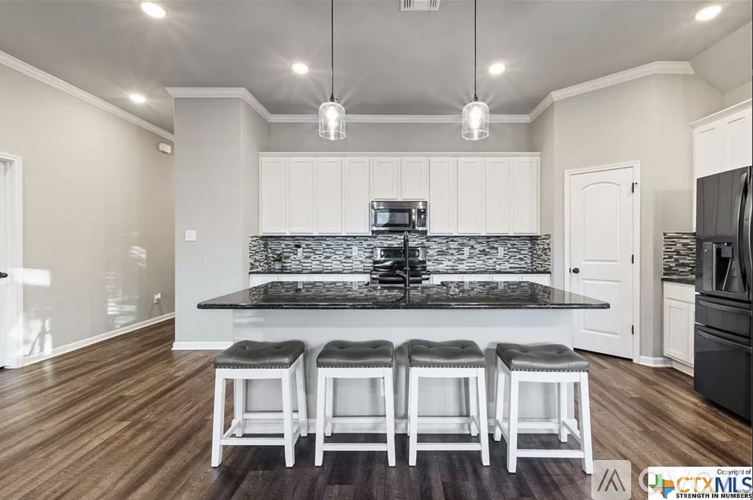 A kitchen with white cabinets and a black countertop.