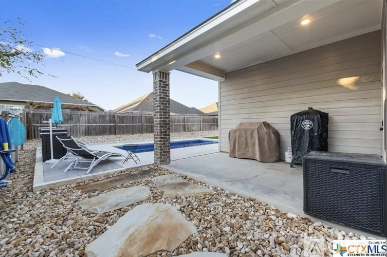A backyard with a pool and patio furniture.