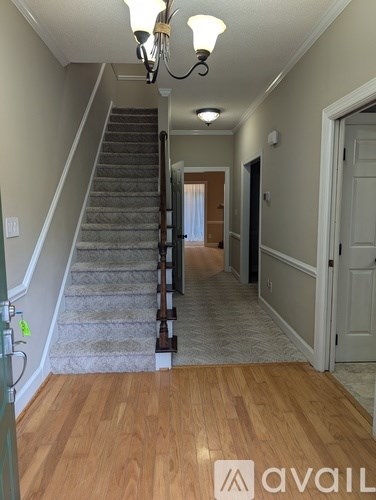 A hallway with a staircase and a chandelier.
