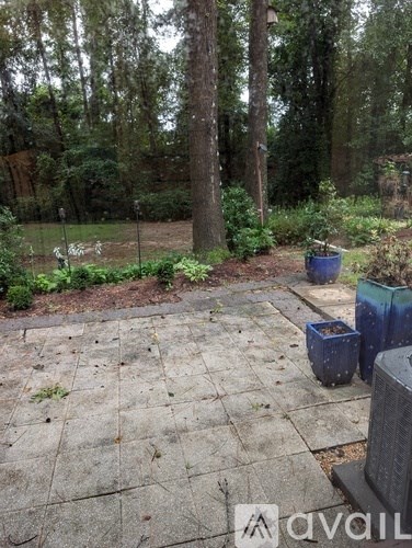 A backyard with a patio, trees, and a fence.