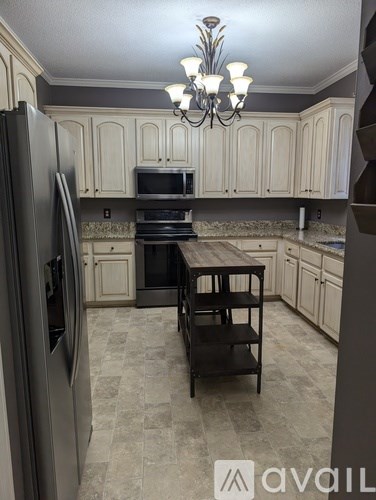 A kitchen with a black refrigerator and a wooden table.