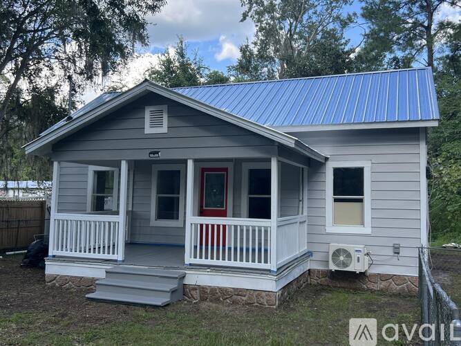 A small house with a porch and a red door.