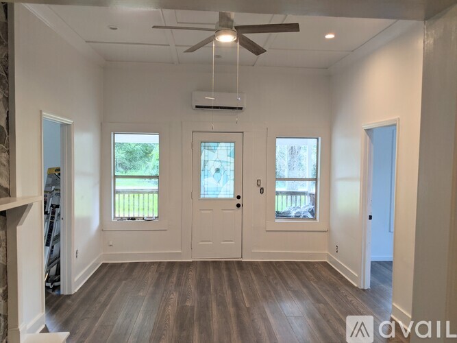 A spacious room with a ceiling fan and three windows.