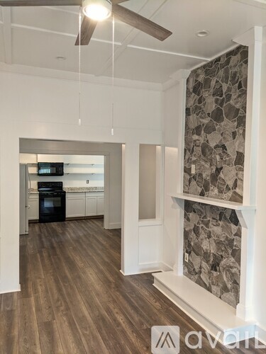 A modern kitchen with wood flooring and a stone fireplace.