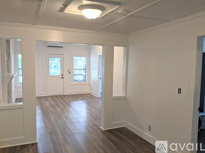 A spacious room with wooden floors and white walls.