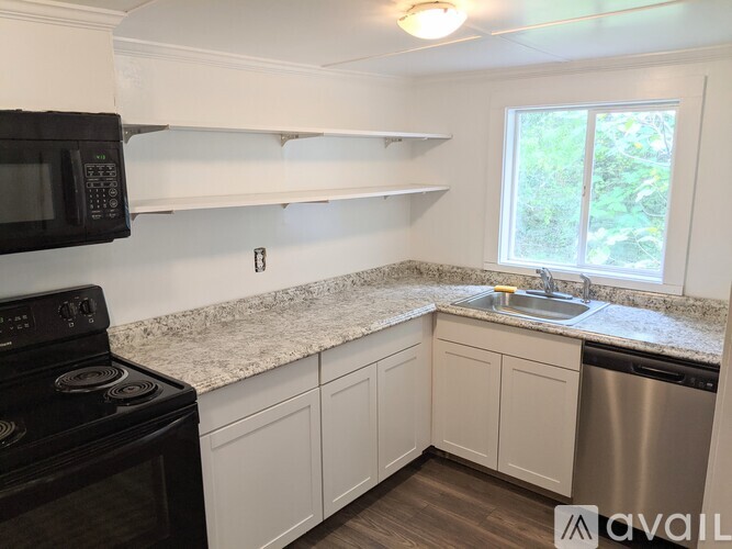 A kitchen with a black stove top oven, white cabinets, and a granite countertop.