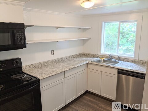 A kitchen with a black stove top oven, white cabinets, and a granite countertop.