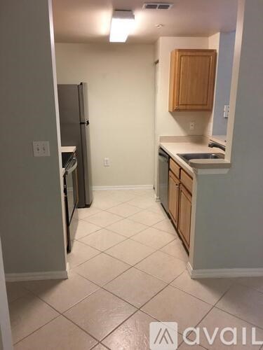 A kitchen with a refrigerator, cabinets, and a counter.