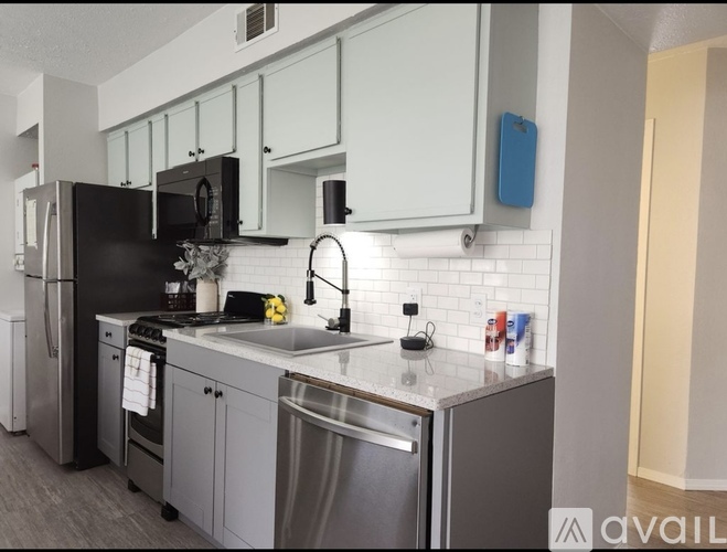A modern kitchen with a black fridge and stainless steel appliances.