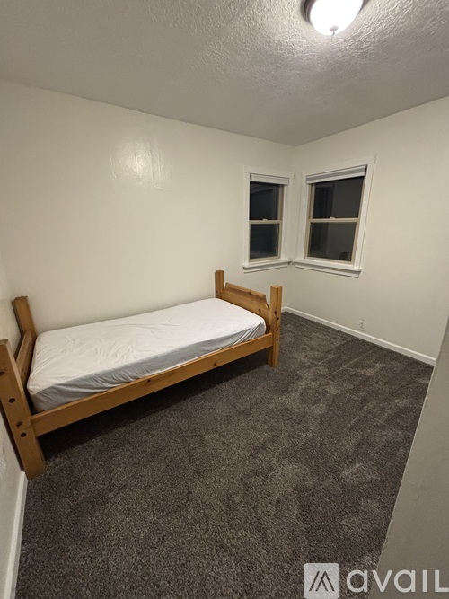 A bedroom with a bed, carpeted floor, and a window.