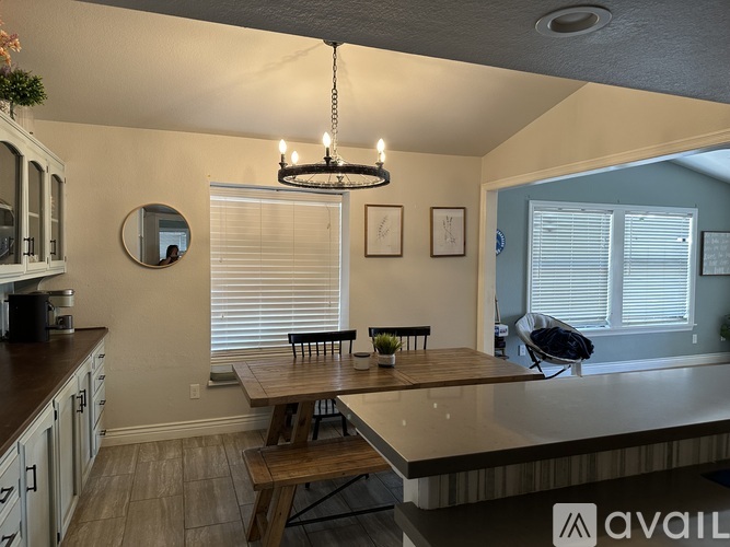 A kitchen with a table and chairs in front of a window with blinds.