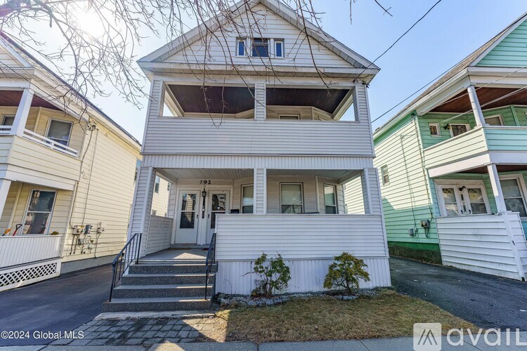 A white two-story house with a front porch and a small front yard.