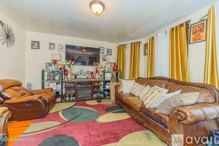 A living room with a brown leather couch and a round rug.
