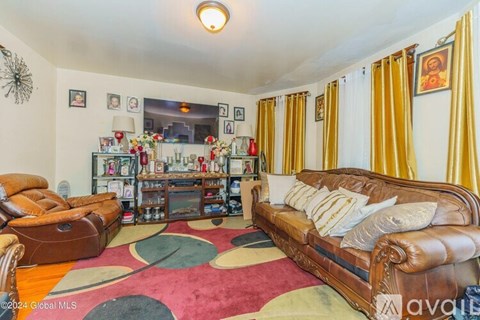 A living room with a brown leather couch and a round rug.