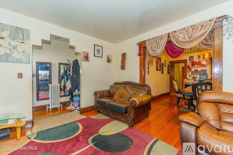 A living room with a brown leather couch and a rug.