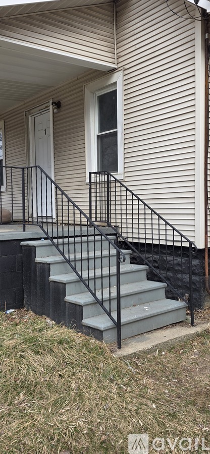 A house with a white door and a black railing on the stairs.