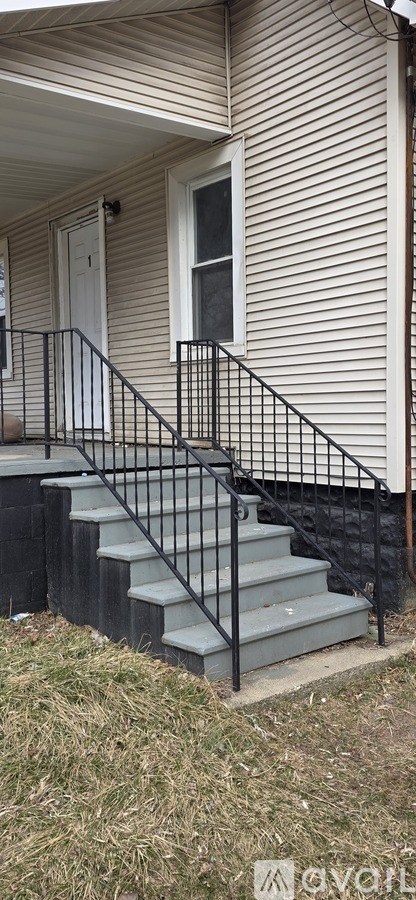 A house with a white door and a black railing on the stairs.