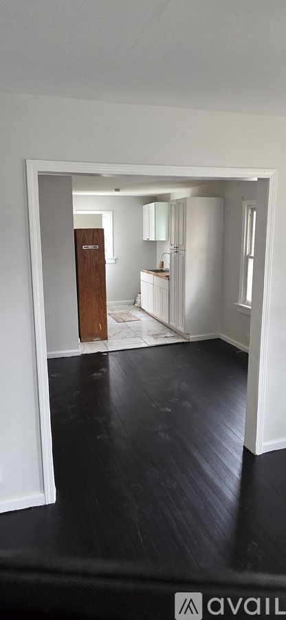 A room with a wooden door and white walls.