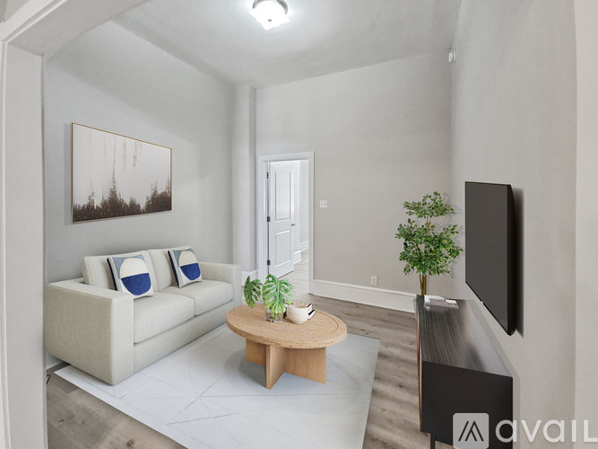 A living room with a couch, a coffee table, a plant, and a television.