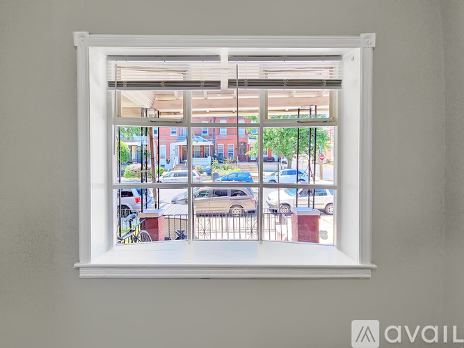 A window with a view of a street with cars and buildings.