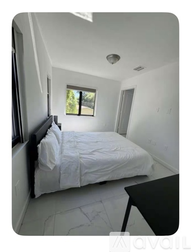 A bedroom with a bed, a window, and a table.