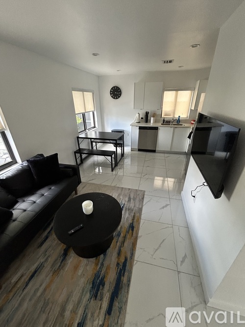 A living room with a black leather couch and a coffee table with a candle on it.