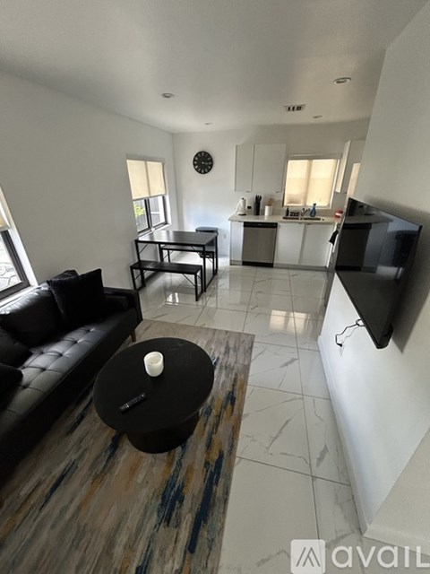 A living room with a black leather couch and a coffee table with a candle on it.
