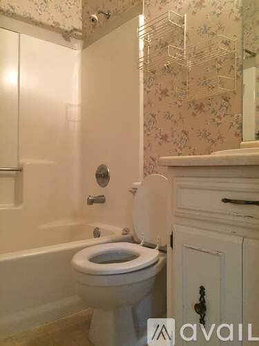 A white toilet in a bathroom with floral wallpaper.