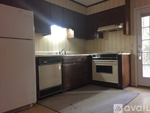 A kitchen with a white refrigerator, dark brown cabinets, and a white oven.