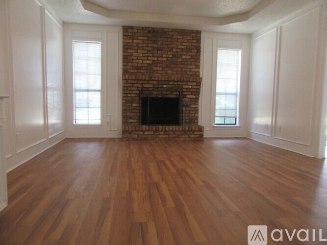 A room with a brick fireplace and wooden floors.