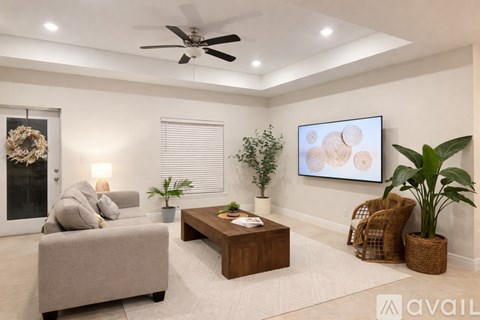 A living room with a grey sofa, a wooden coffee table, a ceiling fan, and a painting on the wall.
