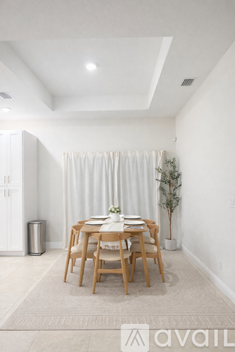 A dining room with a table set for two and a plant in a white pot.