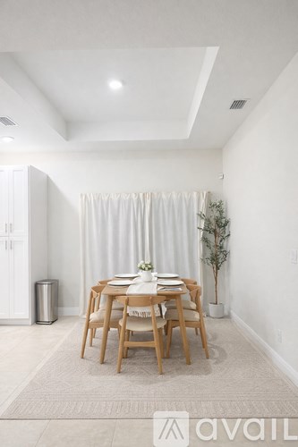 A dining room with a table set for two and a plant in a white pot.