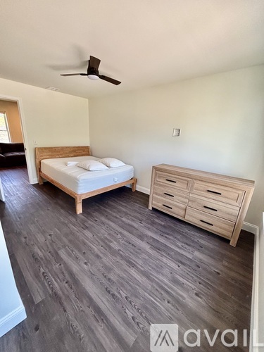 A bedroom with a bed, dresser, and ceiling fan.