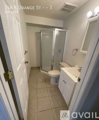 A bathroom with a toilet, sink, and shower stall.